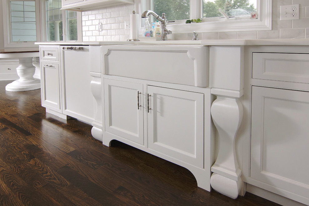 Example of a large transitional u-shaped dark wood floor eat-in kitchen design in New York with white cabinets, white backsplash, an island, a farmhouse sink, beaded inset cabinets, subway tile backsplash and paneled appliances