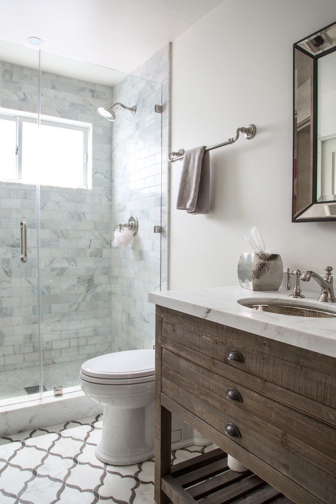 Photo of a transitional bathroom in Los Angeles with an undermount sink, flat-panel cabinets, medium wood cabinets, marble benchtops, an alcove shower, a two-piece toilet, white tile, stone tile, white walls and marble floors.