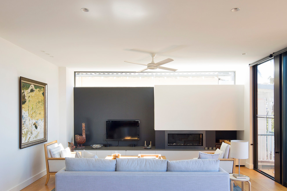 Inspiration for a large contemporary open concept living room in Sydney with white walls, medium hardwood floors, a standard fireplace and a wall-mounted tv.