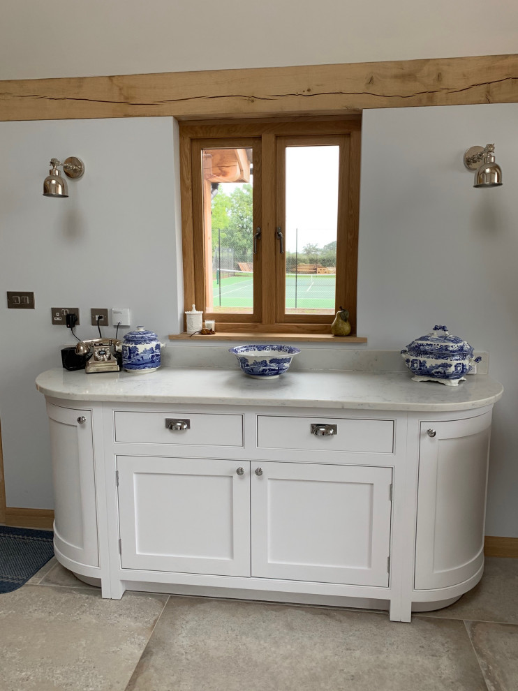 This is an example of a traditional l-shaped eat-in kitchen in Surrey with beaded inset cabinets, white cabinets, quartzite benchtops, with island and white benchtop.