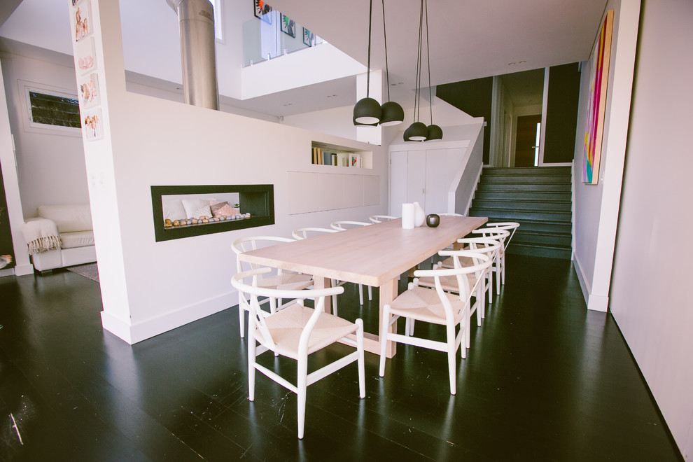 This is an example of a contemporary dining room in Sydney with white walls and a two-sided fireplace.