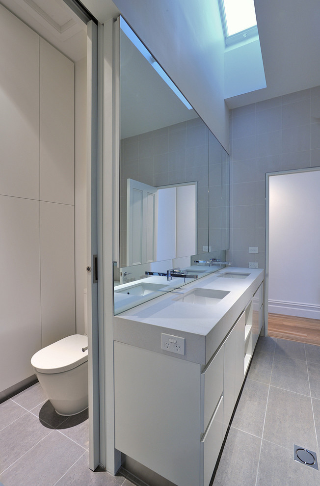 Inspiration for a mid-sized contemporary 3/4 bathroom in Melbourne with an undermount sink, engineered quartz benchtops, a corner shower, beige tile, beige walls, flat-panel cabinets, white cabinets, a drop-in tub, a one-piece toilet, ceramic tile and ceramic floors.