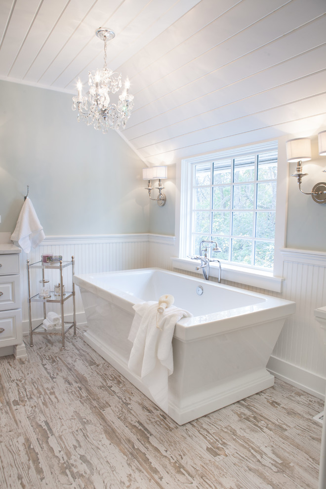 This is an example of a mid-sized country master bathroom in Chicago with an undermount sink, raised-panel cabinets, white cabinets, a two-piece toilet, subway tile, green walls, porcelain floors and a freestanding tub.