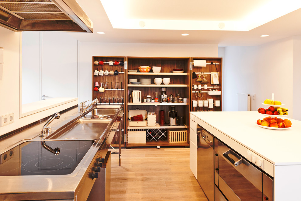 Photo of a mid-sized scandinavian kitchen in Stuttgart with an integrated sink, flat-panel cabinets, white cabinets, medium hardwood floors, with island and stainless steel appliances.