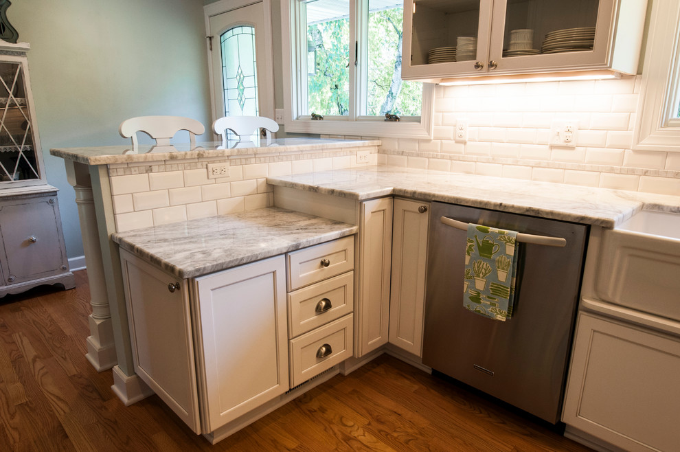 This is an example of a small transitional u-shaped separate kitchen in Milwaukee with a farmhouse sink, shaker cabinets, white cabinets, granite benchtops, white splashback, subway tile splashback, stainless steel appliances, medium hardwood floors and a peninsula.