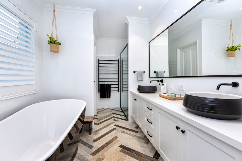 Photo of a mid-sized beach style master bathroom in Perth with shaker cabinets, white cabinets, a freestanding tub, a corner shower, a two-piece toilet, white tile, ceramic tile, white walls, mosaic tile floors, a vessel sink, engineered quartz benchtops, brown floor, a hinged shower door, white benchtops, a double vanity and a built-in vanity.