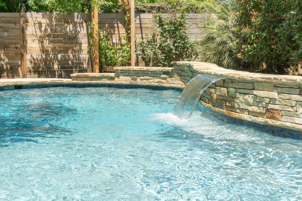 Inspiration for a mid-sized contemporary backyard custom-shaped pool in Austin with a water feature and decking.