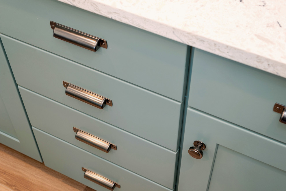 Transitional u-shaped medium tone wood floor and brown floor enclosed kitchen photo with an undermount sink, shaker cabinets, turquoise cabinets, quartzite countertops, gray backsplash, porcelain backsplash, stainless steel appliances, a peninsula and white countertops