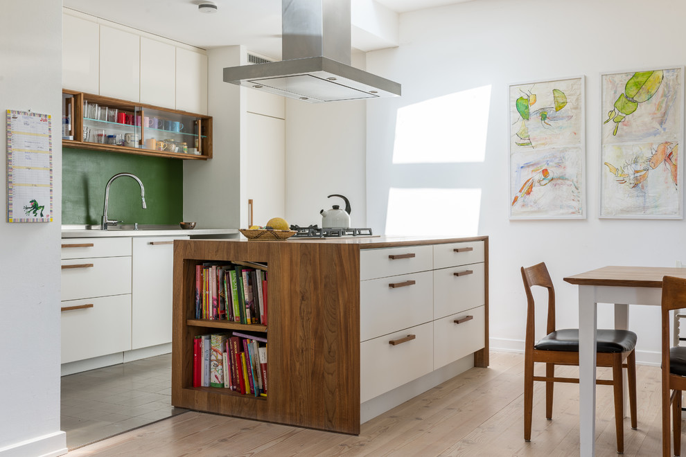 Photo of a large contemporary eat-in kitchen in Hamburg with flat-panel cabinets, white cabinets, green splashback, light hardwood floors, with island and wood benchtops.