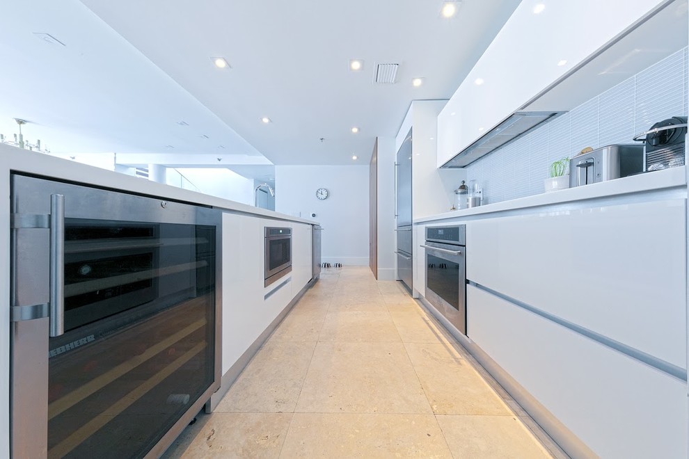 Design ideas for a large modern galley open plan kitchen in Miami with an undermount sink, flat-panel cabinets, white cabinets, solid surface benchtops, white splashback, matchstick tile splashback, stainless steel appliances and with island.