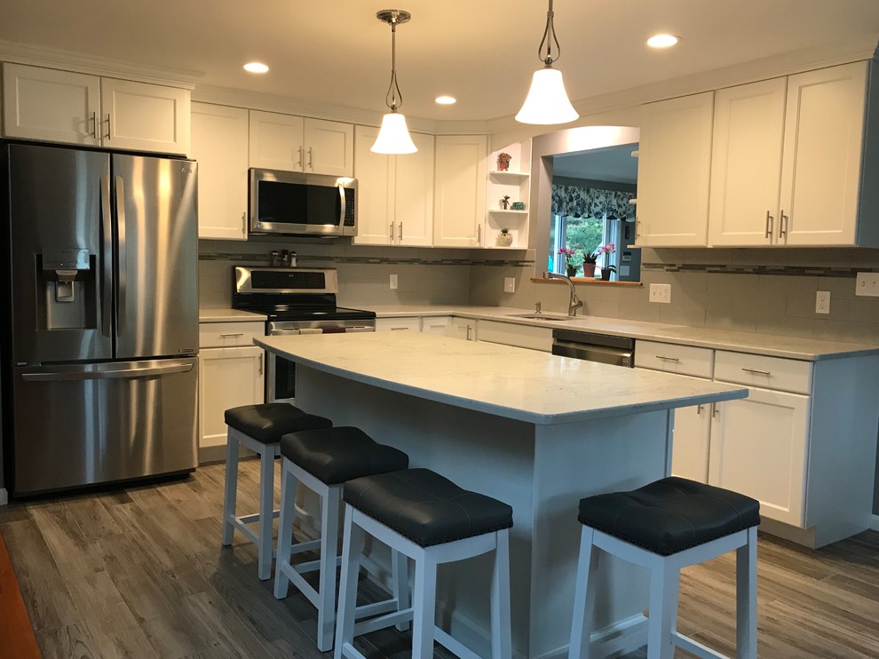 Example of a mid-sized transitional l-shaped porcelain tile and gray floor open concept kitchen design in Boston with a single-bowl sink, flat-panel cabinets, white cabinets, quartz countertops, gray backsplash, subway tile backsplash, stainless steel appliances, an island and white countertops
