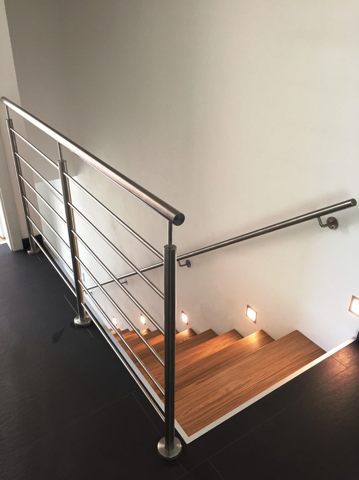 Large modern wood straight staircase in Other with open risers and metal railing.
