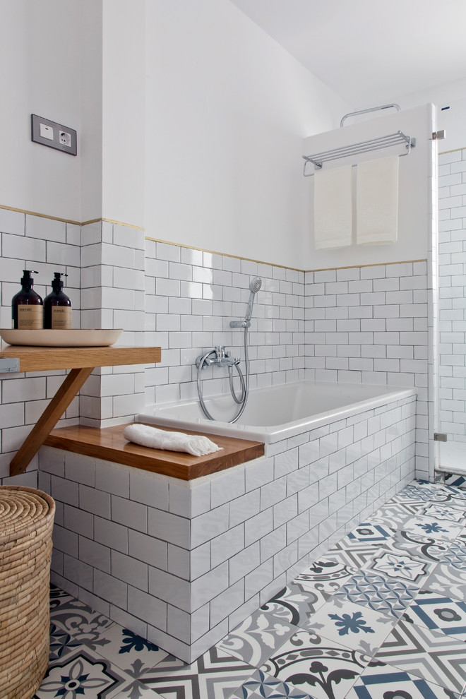 Photo of a mid-sized contemporary master bathroom in Barcelona with open cabinets, medium wood cabinets, a drop-in tub, a shower/bathtub combo, a one-piece toilet, white tile, ceramic tile, white walls, mosaic tile floors, a vessel sink and marble benchtops.