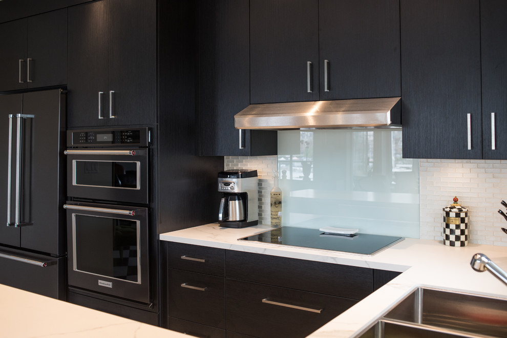 Mid-sized modern u-shaped eat-in kitchen in Vancouver with a double-bowl sink, flat-panel cabinets, dark wood cabinets, marble benchtops, beige splashback, subway tile splashback, stainless steel appliances, linoleum floors, a peninsula and black floor.