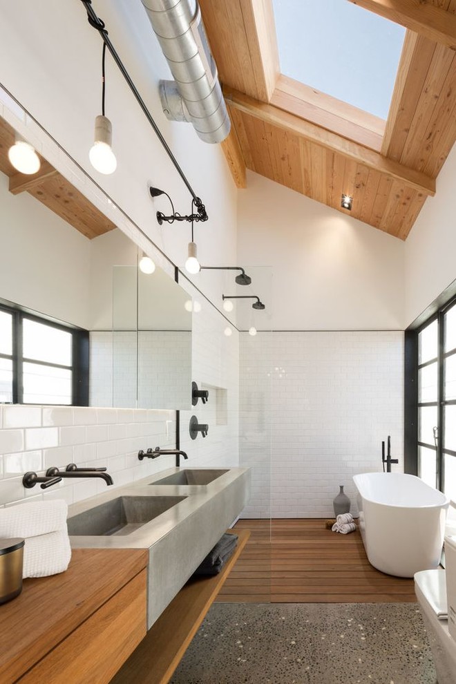 Design ideas for an industrial bathroom in Hawaii with an integrated sink, flat-panel cabinets, medium wood cabinets, concrete benchtops, a freestanding tub, white tile, subway tile, white walls and pebble tile floors.
