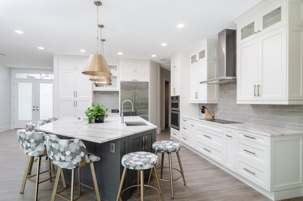 Transitional l-shaped gray floor kitchen photo with an undermount sink, recessed-panel cabinets, white cabinets, gray backsplash, stainless steel appliances, an island and white countertops
