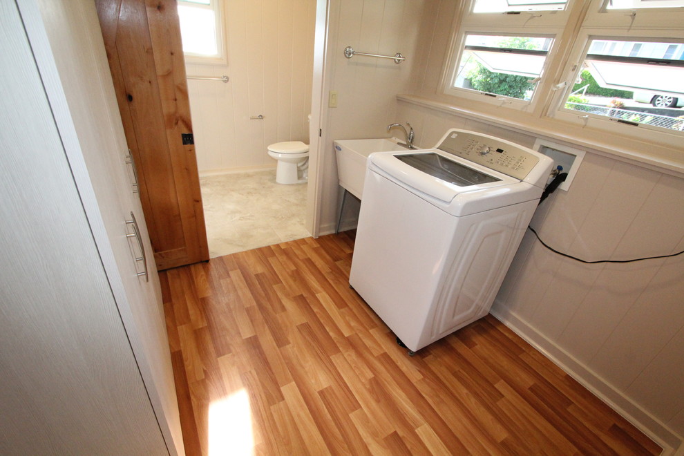 This is an example of a medium sized traditional single-wall utility room in Hawaii with an utility sink, white walls, medium hardwood flooring and a side by side washer and dryer.