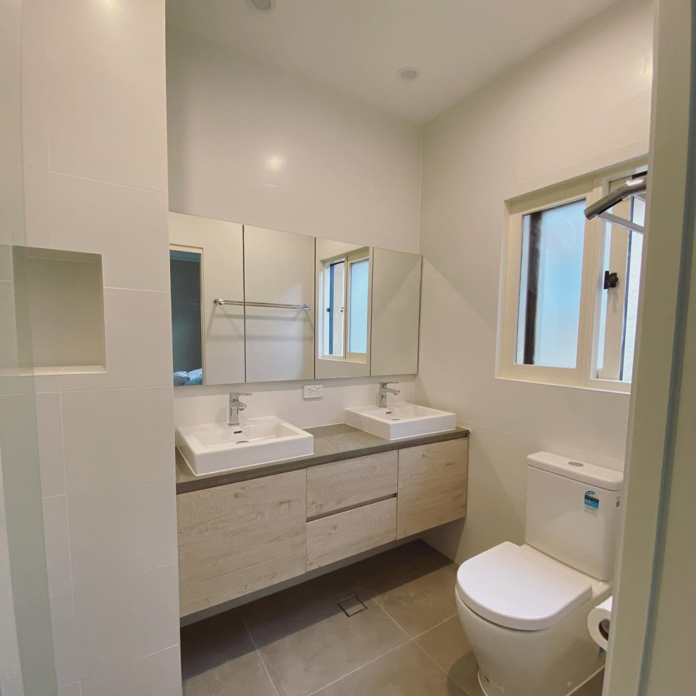 Small contemporary master wet room bathroom in Sydney with furniture-like cabinets, grey cabinets, a corner tub, a one-piece toilet, white tile, porcelain tile, white walls, porcelain floors, a vessel sink, engineered quartz benchtops, grey floor, an open shower, grey benchtops, a niche, a double vanity, a floating vanity, recessed and brick walls.