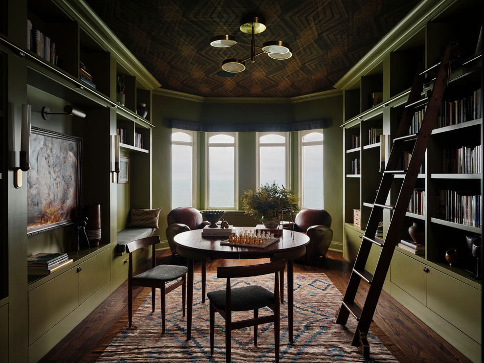 This is an example of an eclectic home office in Chicago with a library, green walls, medium hardwood floors, a freestanding desk, brown floor and wallpaper.