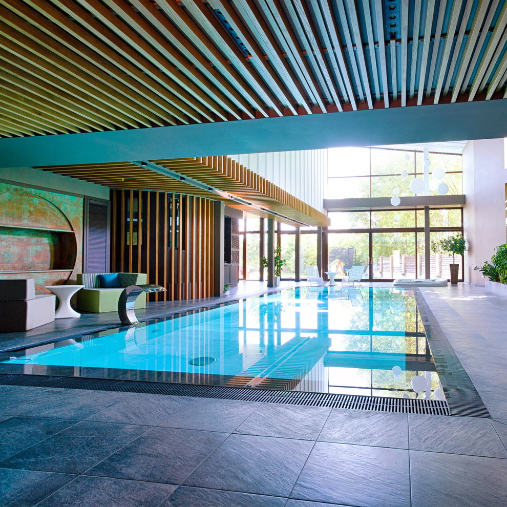 Large industrial indoor rectangular infinity pool in Other with a water feature and tile.