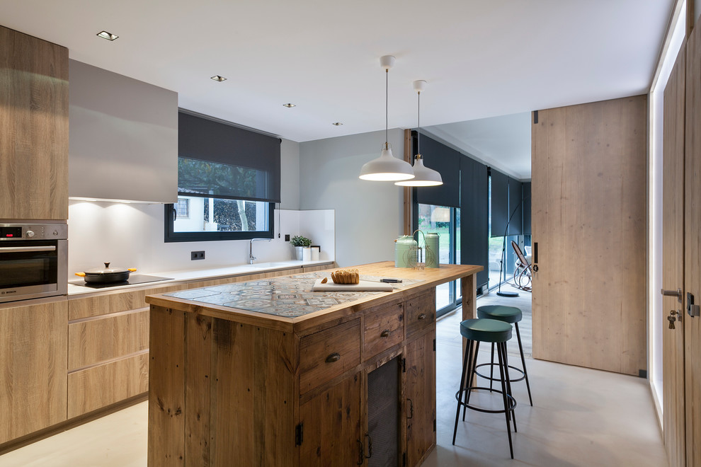 Inspiration for a large contemporary galley separate kitchen in Barcelona with an integrated sink, flat-panel cabinets, light wood cabinets, stainless steel appliances, concrete floors, with island, tile benchtops and white splashback.