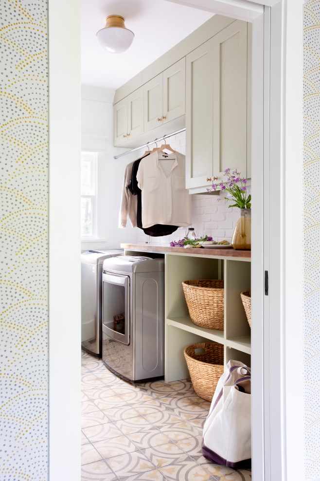 Inspiration for a beach style dedicated laundry room in Charleston with shaker cabinets, green cabinets, wood benchtops, white splashback, white walls, a side-by-side washer and dryer, multi-coloured floor and brown benchtop.