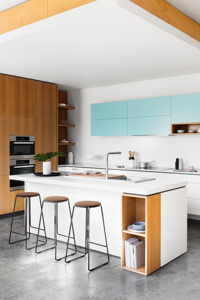 This is an example of a mid-sized contemporary kitchen in Melbourne with a drop-in sink, flat-panel cabinets, white cabinets, stainless steel appliances, concrete floors and with island.