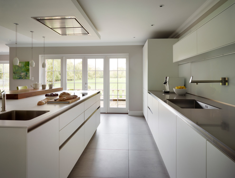 Photo of a large contemporary l-shaped eat-in kitchen in Surrey with an integrated sink, flat-panel cabinets, white cabinets, quartz benchtops, white splashback, glass sheet splashback, stainless steel appliances, ceramic floors and with island.