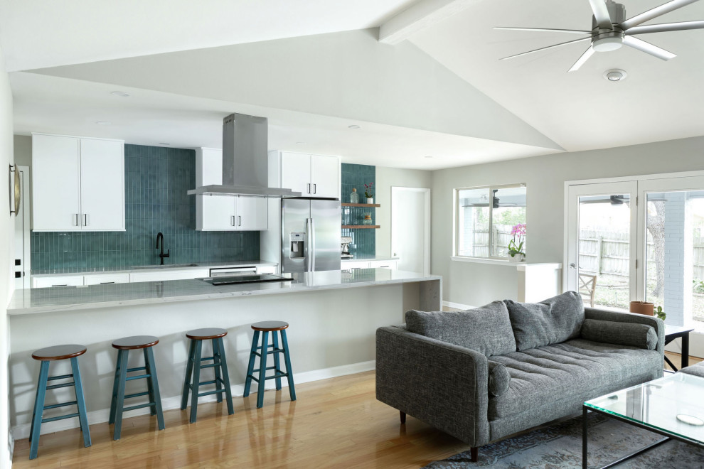 Mid-sized transitional galley light wood floor, yellow floor and vaulted ceiling eat-in kitchen photo in Austin with an undermount sink, shaker cabinets, white cabinets, quartzite countertops, blue backsplash, subway tile backsplash, stainless steel appliances, a peninsula and gray countertops