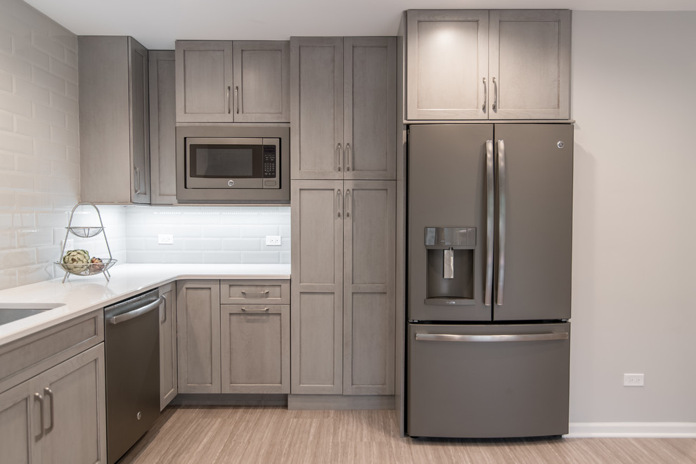 Mid-sized transitional u-shaped vinyl floor and gray floor enclosed kitchen photo in Chicago with an undermount sink, recessed-panel cabinets, gray cabinets, quartzite countertops, gray backsplash, subway tile backsplash and stainless steel appliances