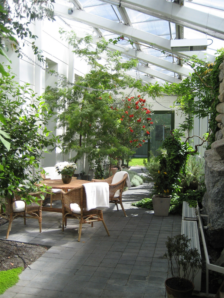 This is an example of a mid-sized contemporary side yard patio in Stockholm with a vertical garden, a roof extension and concrete slab.