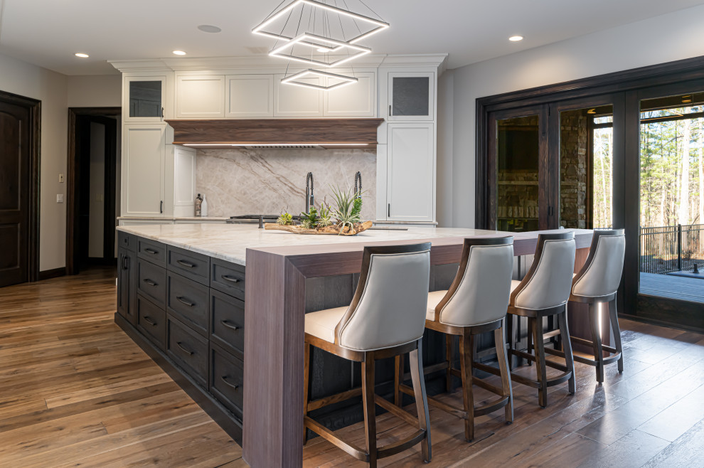 Inspiration for a large transitional medium tone wood floor and brown floor open concept kitchen remodel with a double-bowl sink, flat-panel cabinets, white cabinets, quartzite countertops, beige backsplash, stainless steel appliances, an island and beige countertops