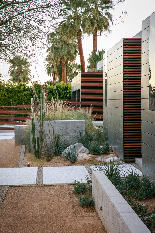 Large midcentury front yard full sun xeriscape in San Diego with a retaining wall and gravel.
