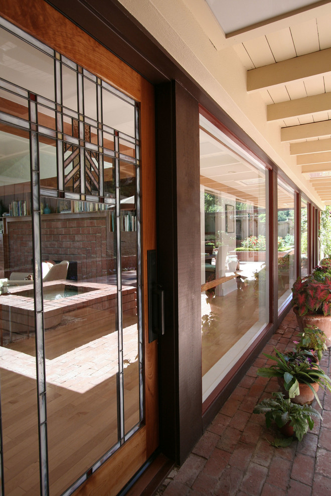 Photo of a midcentury front door in San Diego with brick floors, a single front door and a medium wood front door.