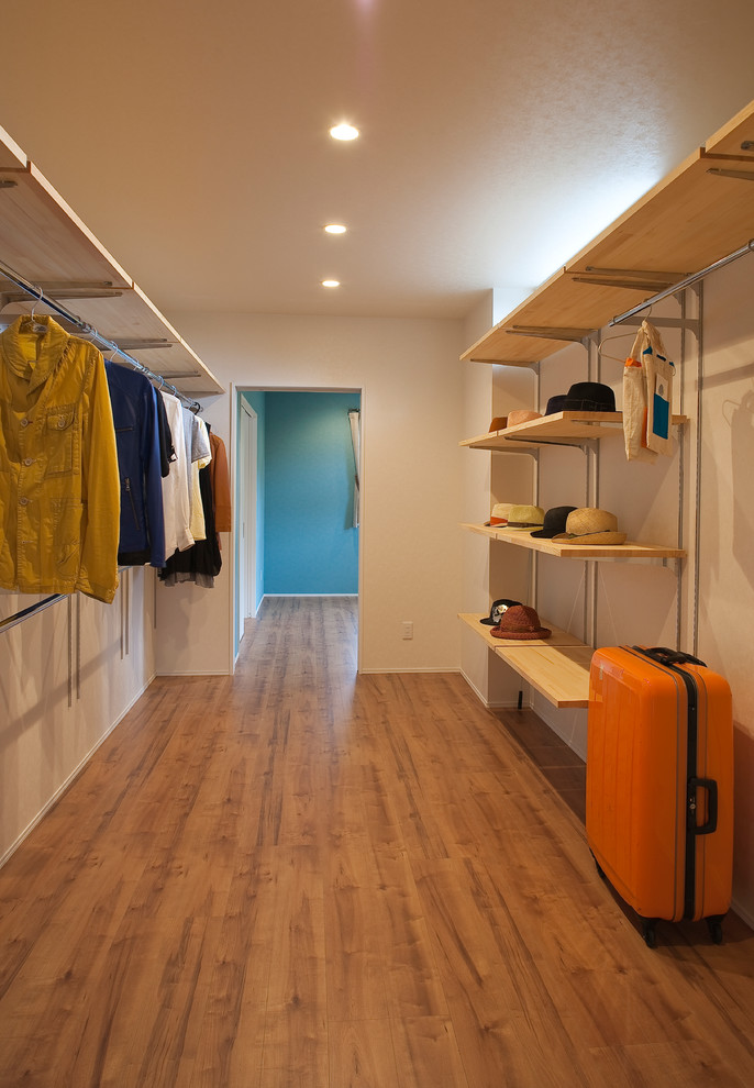 This is an example of a mid-sized modern gender-neutral storage and wardrobe in Other with plywood floors, brown floor and open cabinets.
