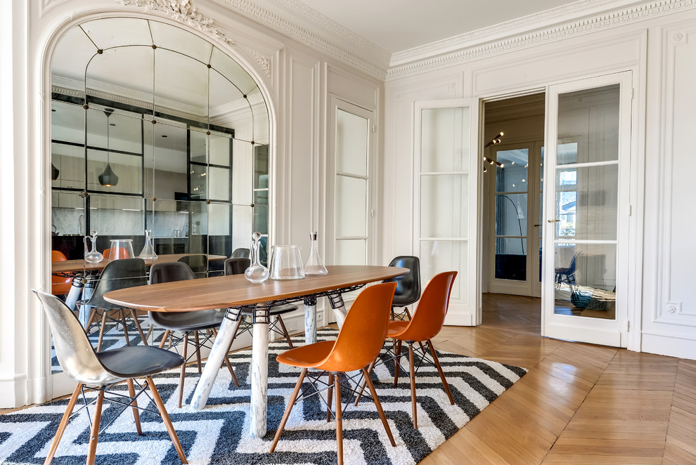 This is an example of a mid-sized contemporary separate dining room in Paris with white walls, medium hardwood floors and no fireplace.