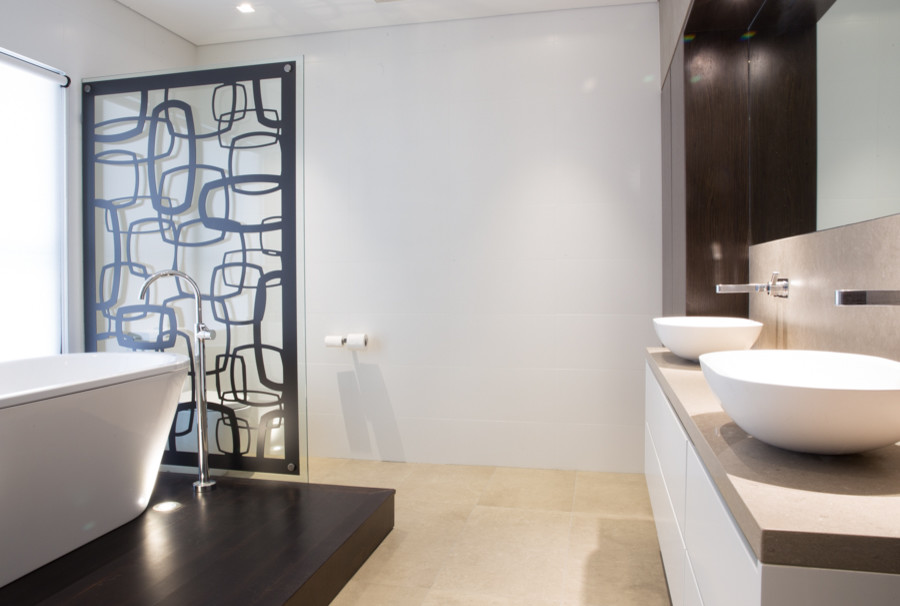 This is an example of a mid-sized contemporary master bathroom in Sydney with a vessel sink, furniture-like cabinets, dark wood cabinets, solid surface benchtops, a freestanding tub, a double shower, a one-piece toilet, white tile, ceramic tile, white walls and ceramic floors.