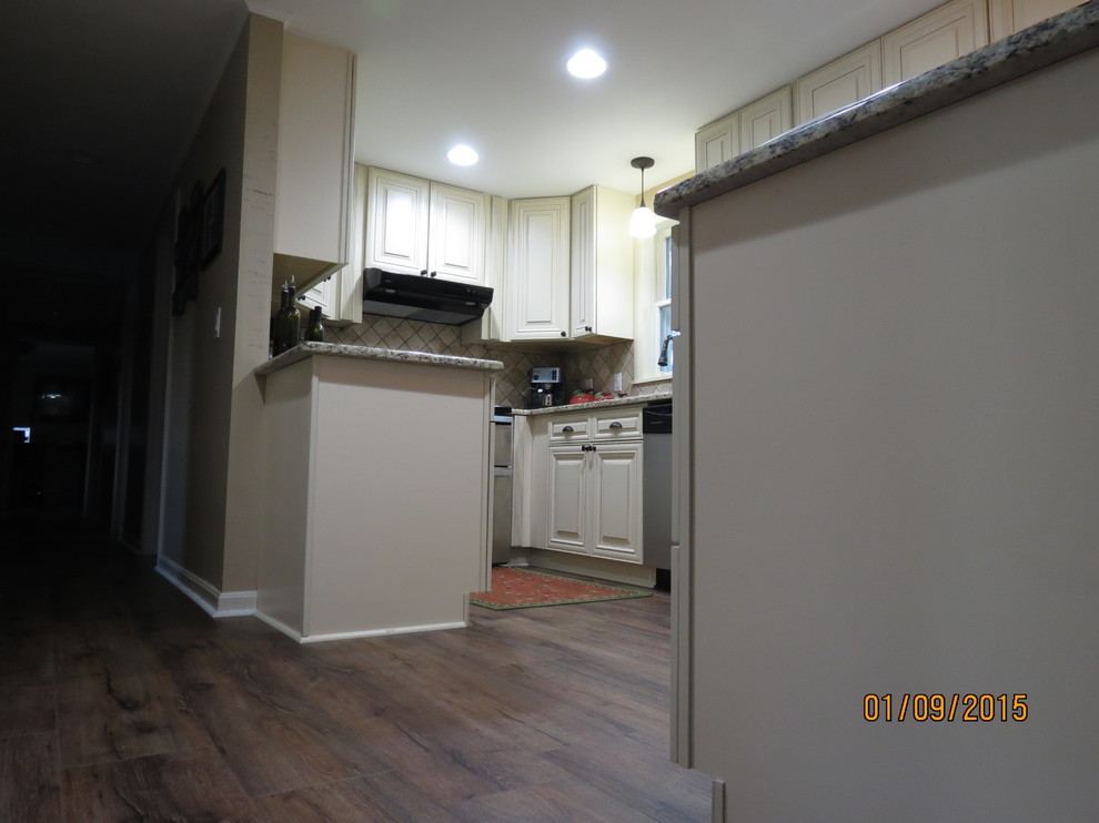 Example of a mid-sized u-shaped eat-in kitchen design in DC Metro with a double-bowl sink, raised-panel cabinets, white cabinets, granite countertops, beige backsplash, porcelain backsplash and stainless steel appliances