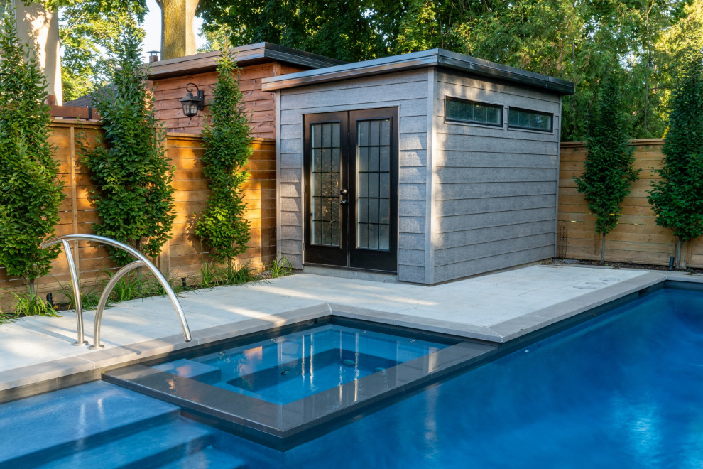 Photo of a small transitional backyard rectangular pool in Toronto with a pool house and stamped concrete.