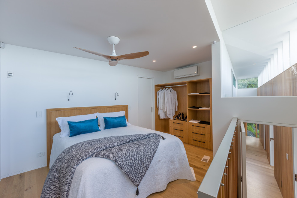 Diseño de habitación de invitados contemporánea de tamaño medio con paredes blancas, suelo de madera clara y suelo marrón