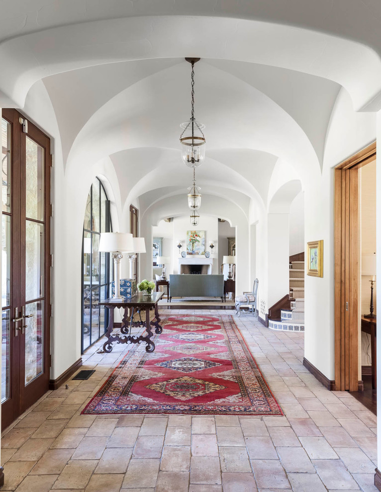 Expansive mediterranean hallway in Dallas with white walls and brick floors.
