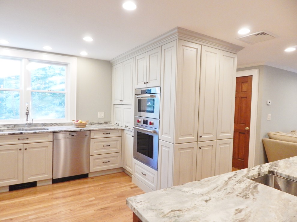 Inspiration for a mid-sized transitional l-shaped light wood floor open concept kitchen remodel in Boston with an undermount sink, raised-panel cabinets, white cabinets, quartzite countertops, stainless steel appliances and an island