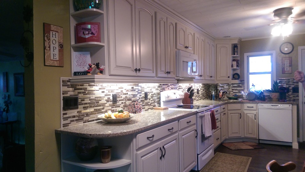 Eat-in kitchen - mid-sized transitional l-shaped laminate floor eat-in kitchen idea with an undermount sink, raised-panel cabinets, white cabinets, granite countertops, multicolored backsplash, mosaic tile backsplash, white appliances and no island