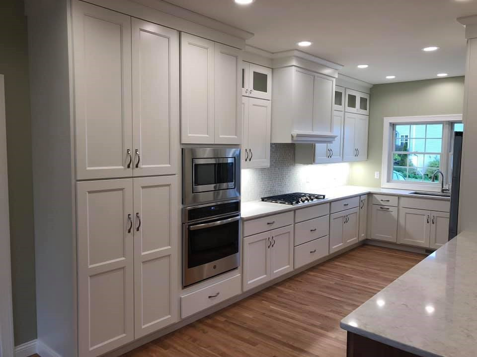 Inspiration for a large transitional l-shaped medium tone wood floor kitchen remodel with an undermount sink, shaker cabinets, white cabinets, quartz countertops, stainless steel appliances, a peninsula and white countertops