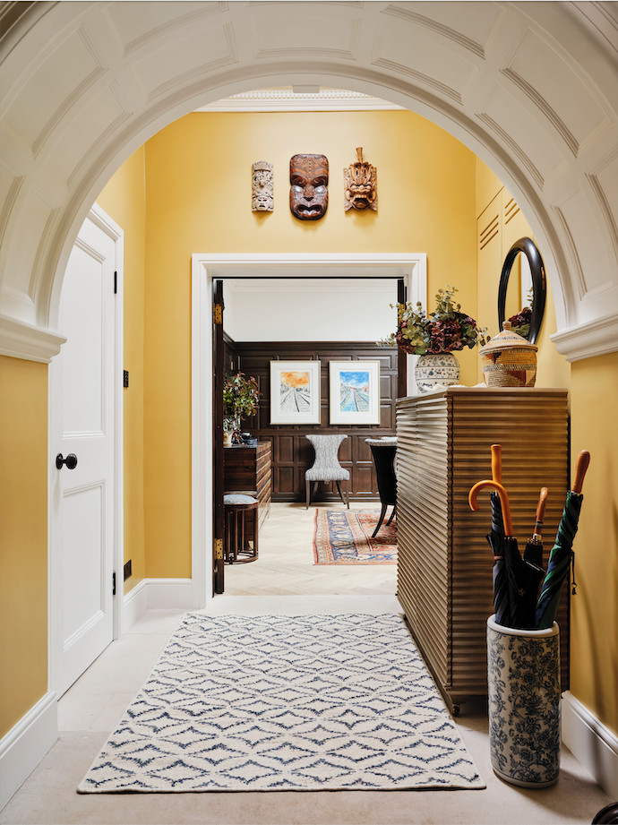 This is an example of a transitional entry hall in London with yellow walls, porcelain floors and timber.