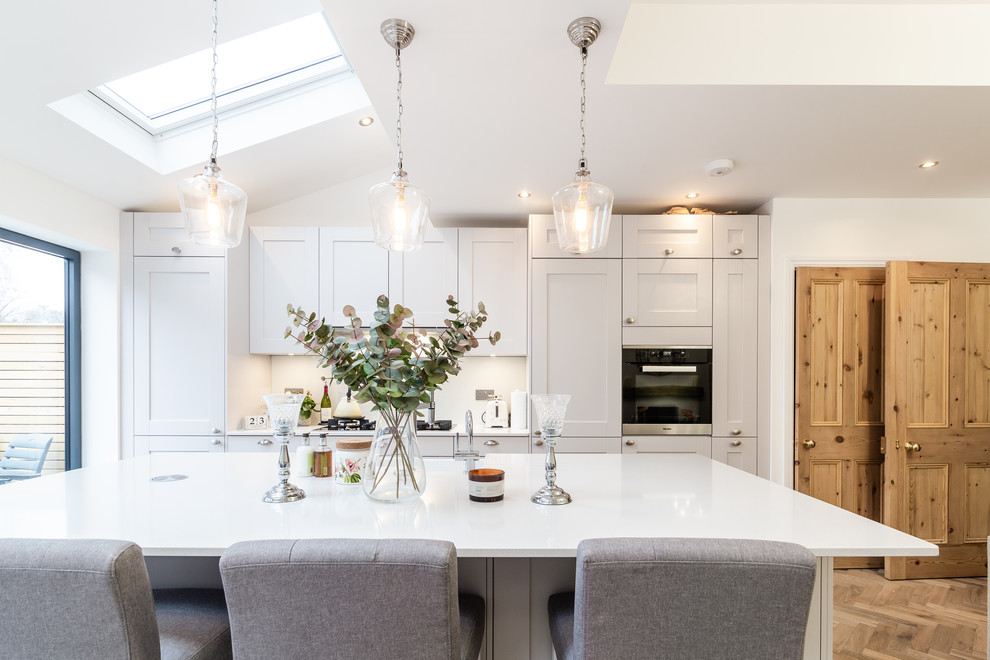 Inspiration for a large modern kitchen in London with a farmhouse sink, shaker cabinets, quartzite benchtops, white splashback, glass sheet splashback and with island.