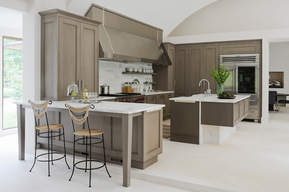 This is an example of a transitional l-shaped kitchen in Atlanta with recessed-panel cabinets, white splashback, stainless steel appliances and with island.