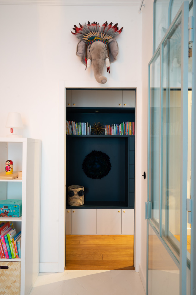 Small scandinavian kids' room in Paris with white walls, light hardwood floors and brown floor for girls.