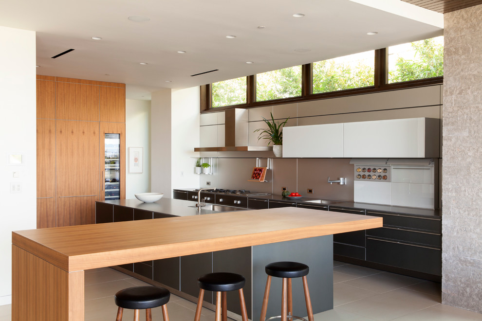 This is an example of a large contemporary l-shaped eat-in kitchen in Los Angeles with an undermount sink, flat-panel cabinets, grey cabinets, wood benchtops, metal splashback, panelled appliances, porcelain floors, multiple islands and metallic splashback.