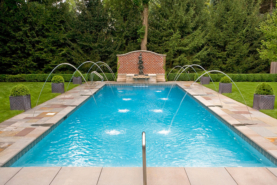 Photo of a large traditional backyard rectangular lap pool in Chicago with a water feature and natural stone pavers.